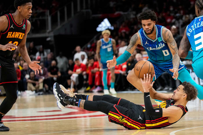 Apr 13, 2022; Atlanta, Georgia, USA; Atlanta Hawks guard Trae Young (11) passes the ball from the floor to forward De'Andre Hunter (12) behind Charlotte Hornets forward Miles Bridges (0) during the second half at State Farm Arena.